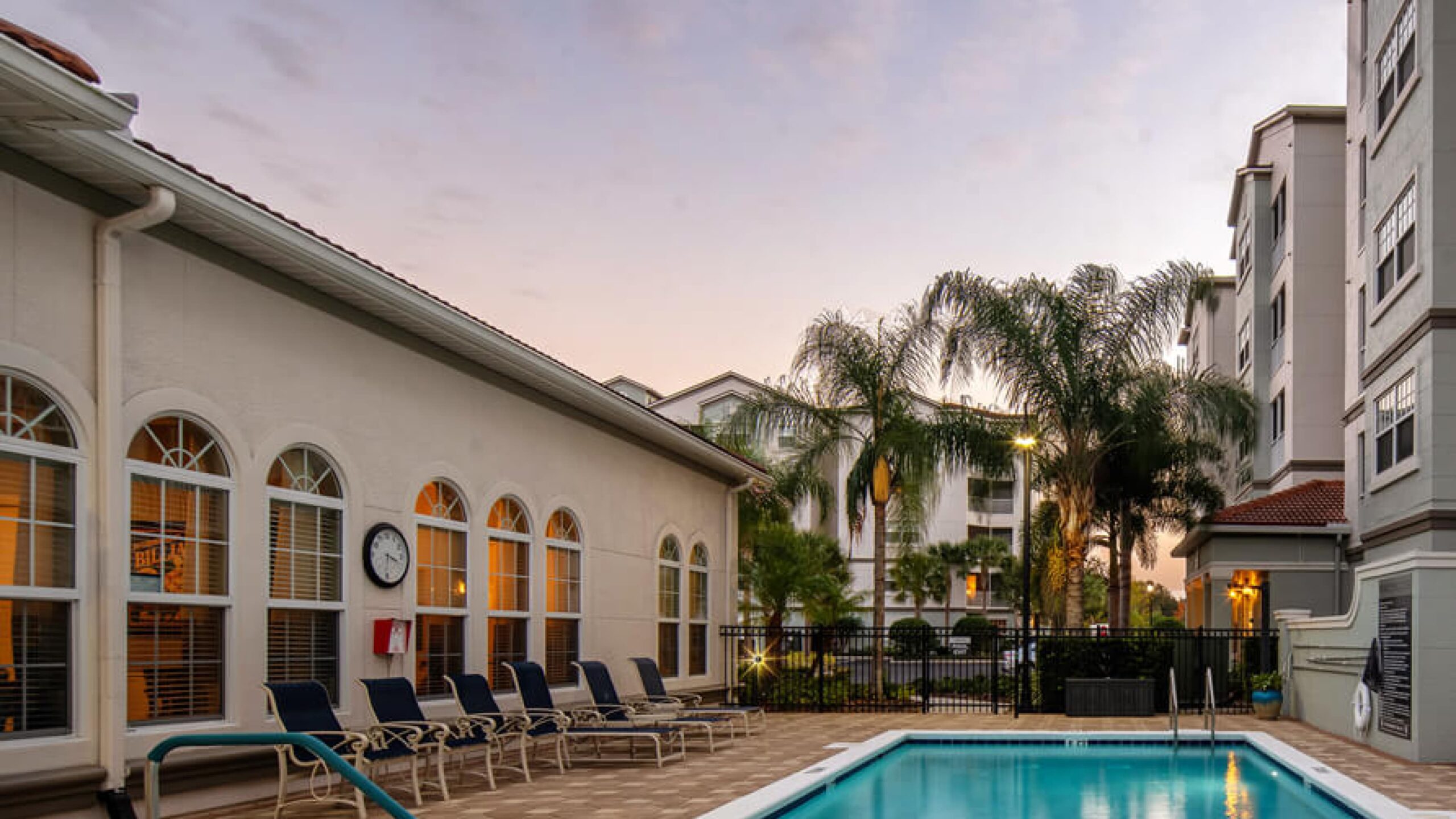 Outdoor pool area with lounge chairs and palm trees