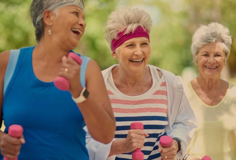 Three women enjoying outdoor exercise with weights