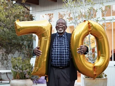 A resident celebrating with large gold balloons marking their birthday