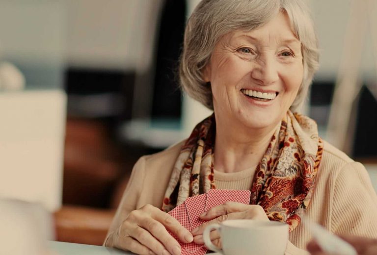 Senior woman playing cards and smiling in a common area