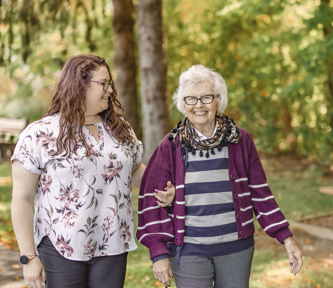 A staff member walking with a resident in a garden