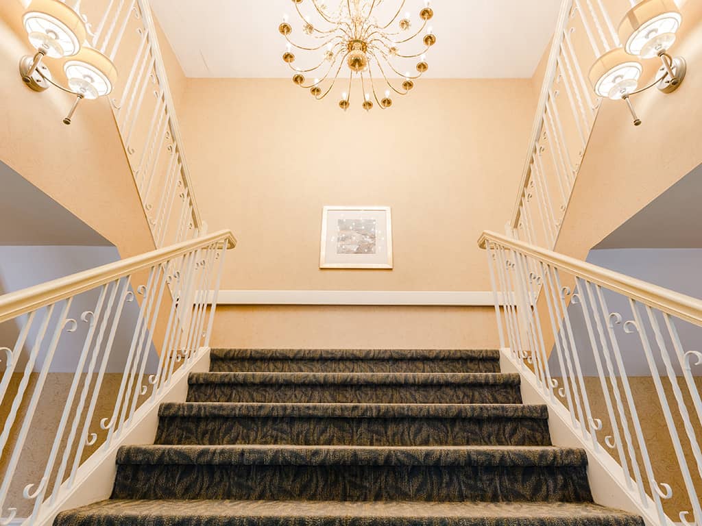 Interior staircase with chandelier and wall decor
