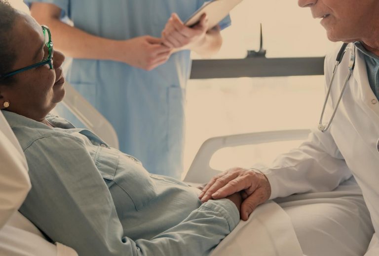 A doctor consulting with a resident in a facility room.