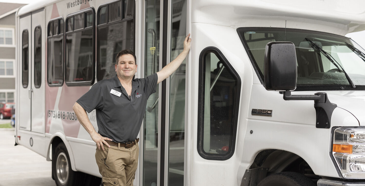Staff member posing with facility transport vehicle