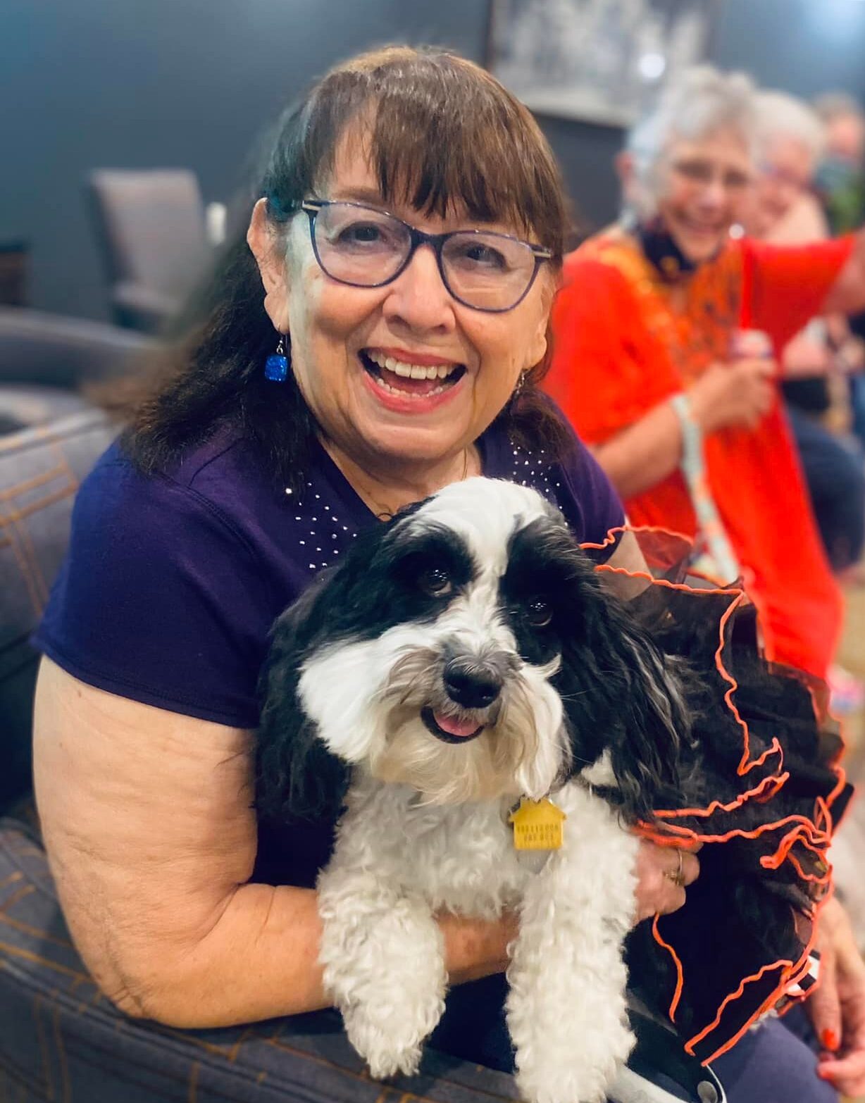 Resident happily holding a dog in a social setting
