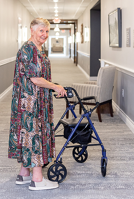A resident walking with a walker in a hallway