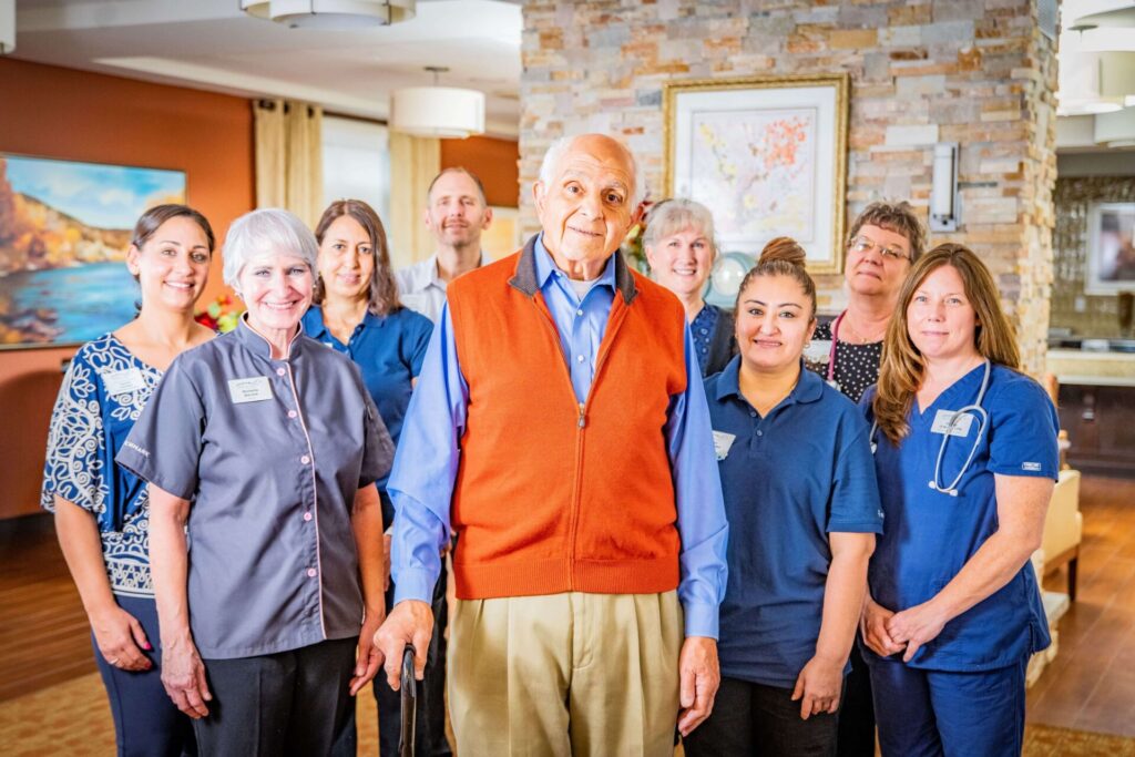 A group photo of staff with a resident in a common area