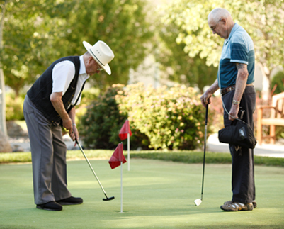 Two seniors playing golf on a putting green