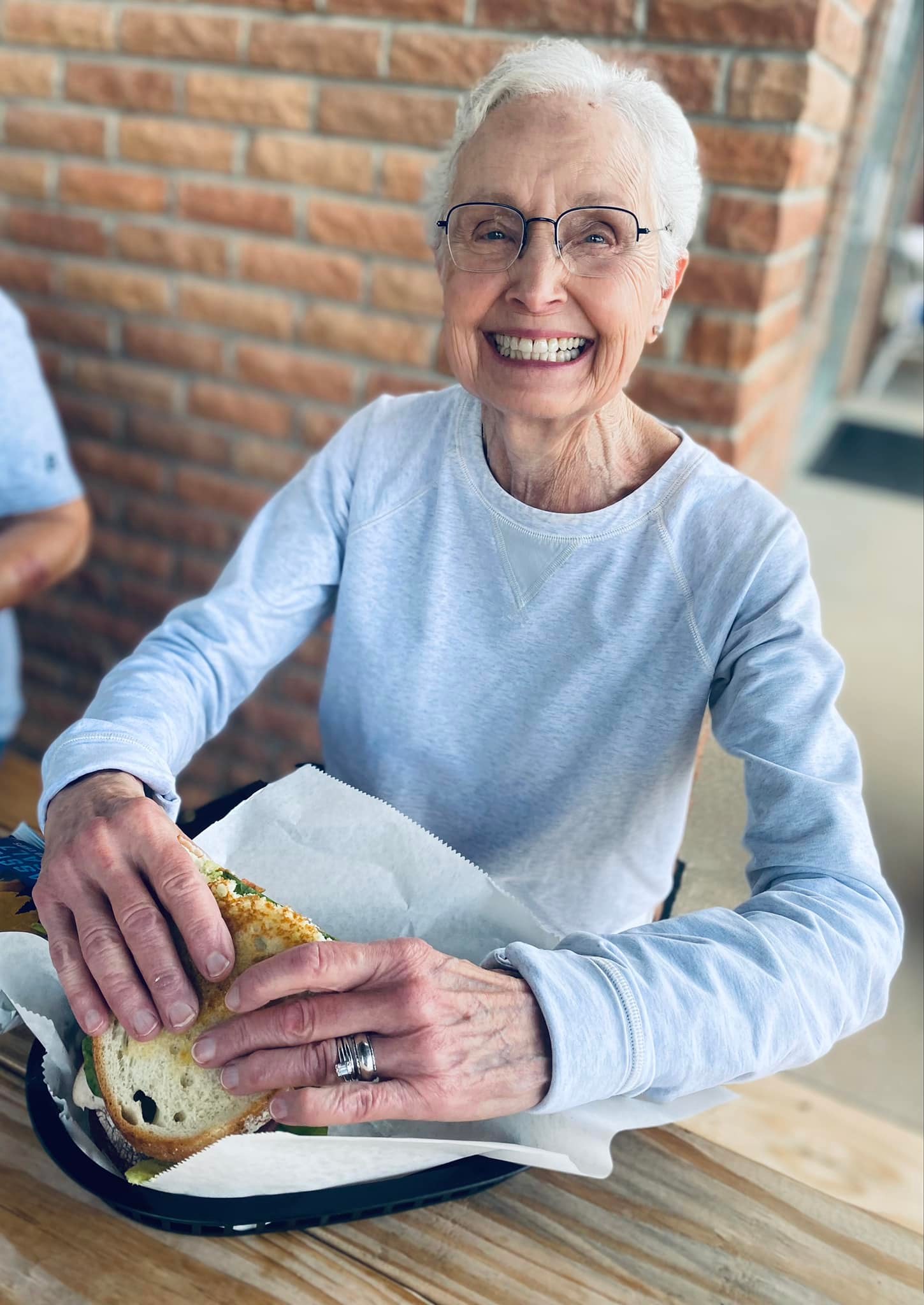Senior resident enjoying a sandwich with a big smile