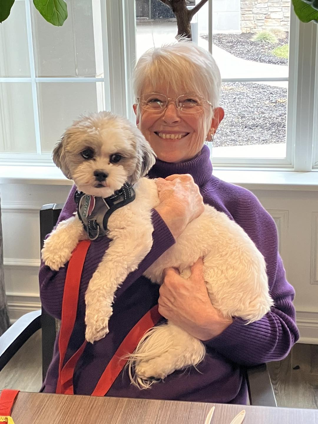 A resident holding a small dog in a cozy setting