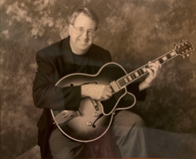Musician playing guitar smiling at the camera