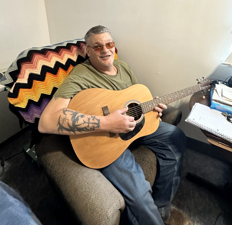 Resident playing guitar in common area