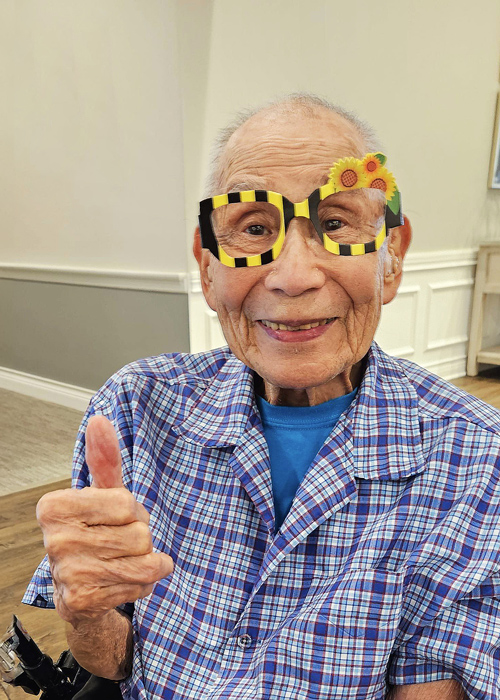 Resident wearing playful glasses and giving a thumbs up
