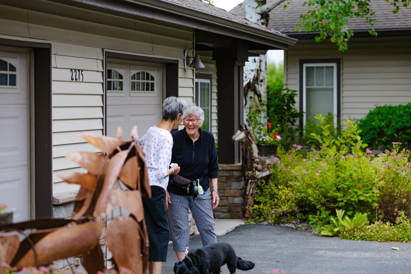 Two residents chatting outside with a dog