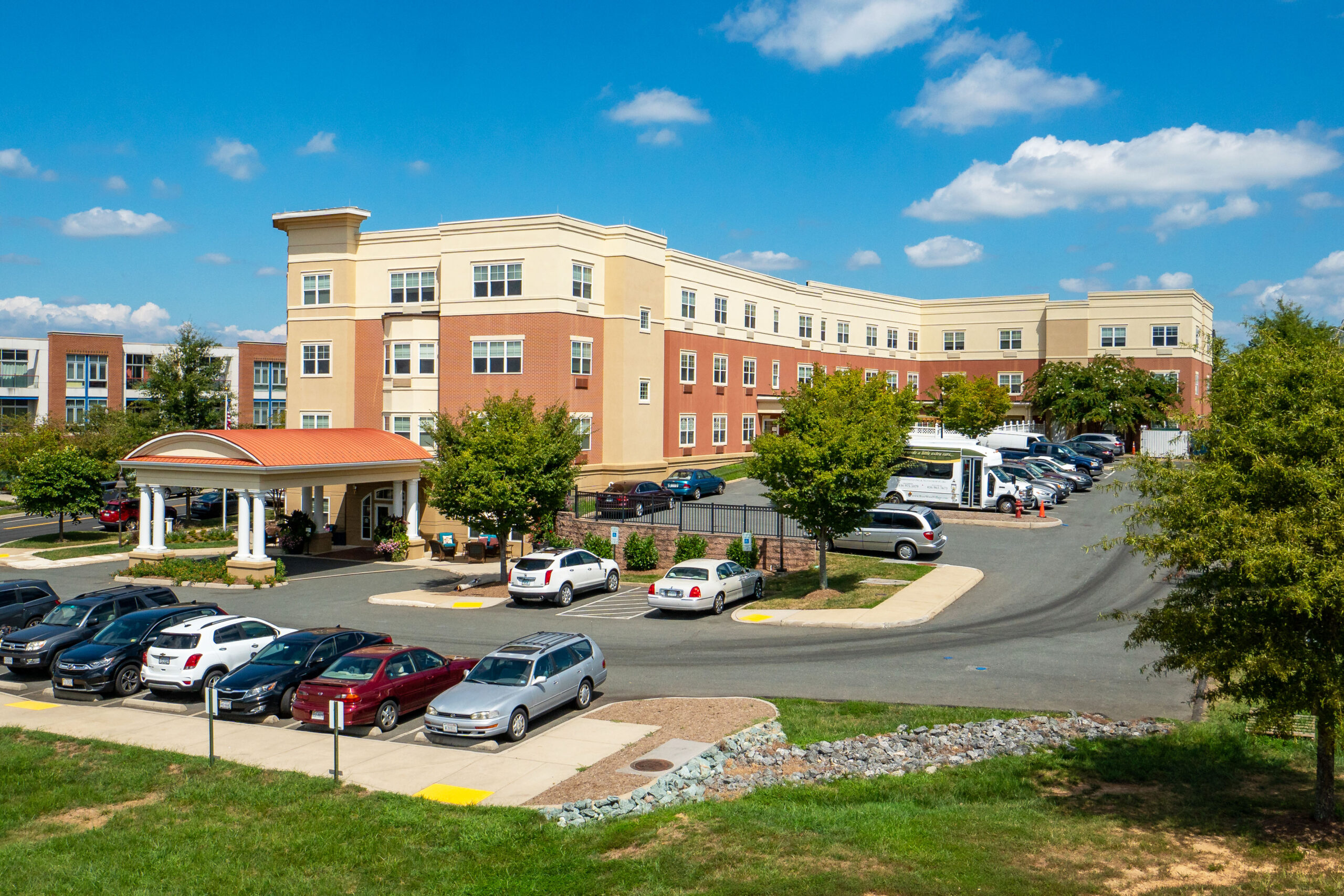 Exterior view of a senior living facility with parked cars