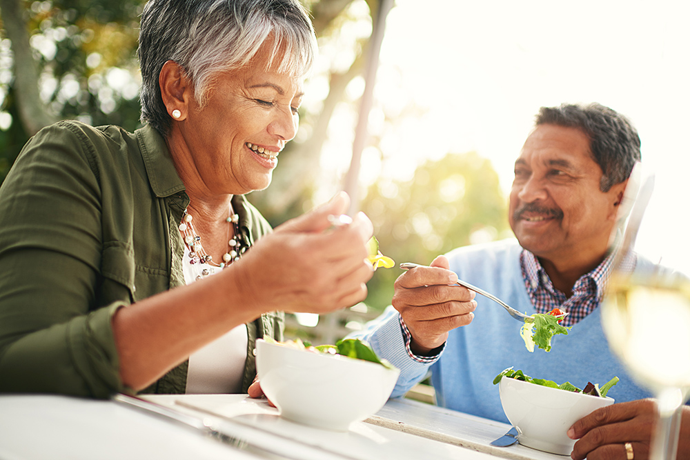 Couple enjoying a meal outdoors with salads