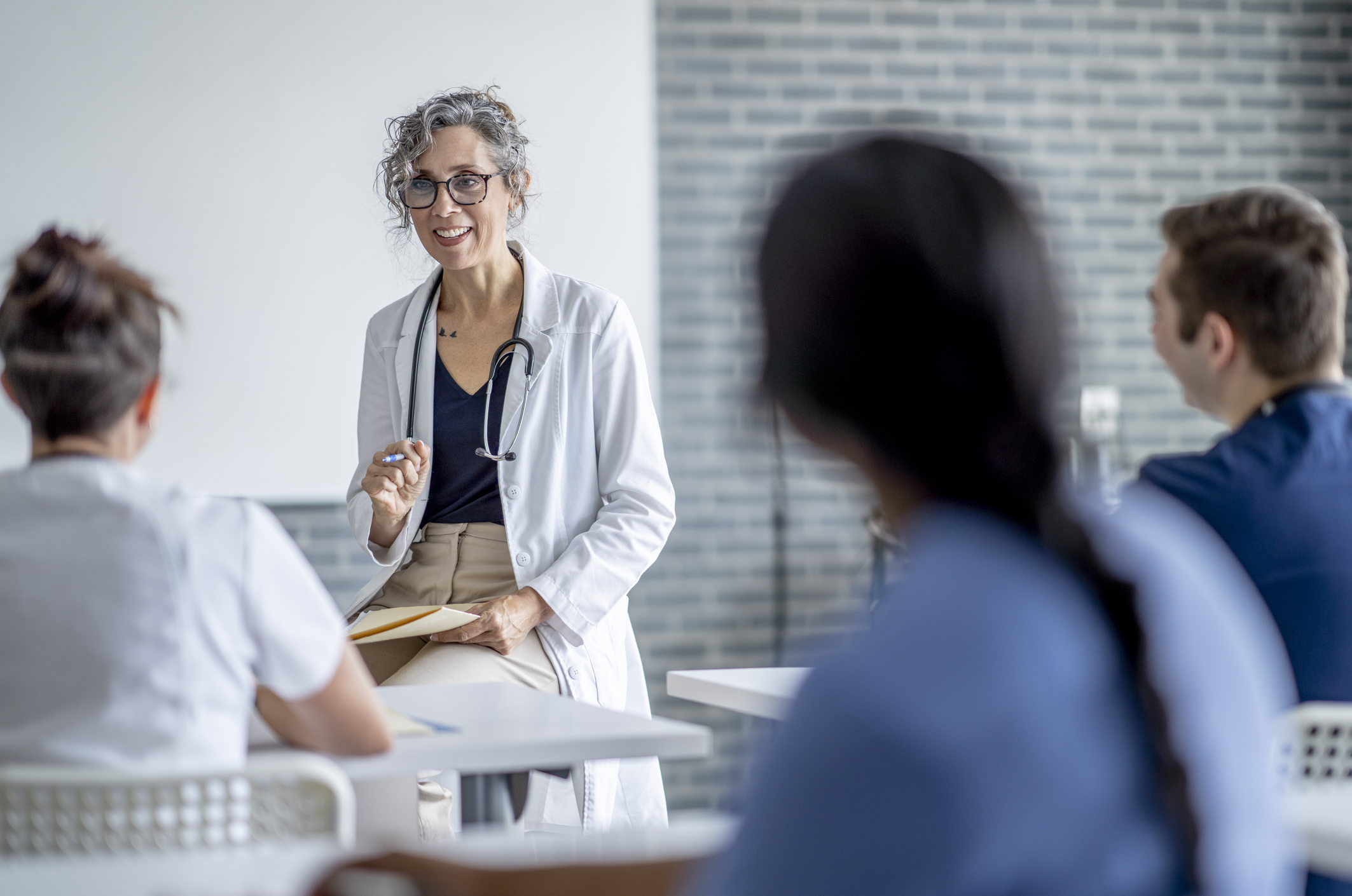 A doctor speaking to a group in a bright classroom