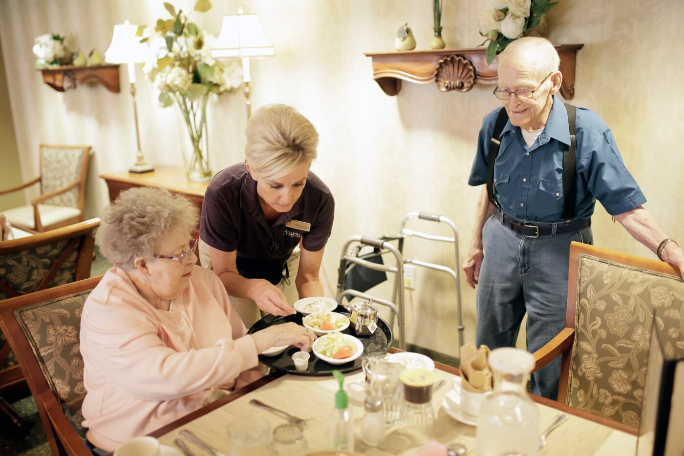 A staff member serving food to residents in a dining room