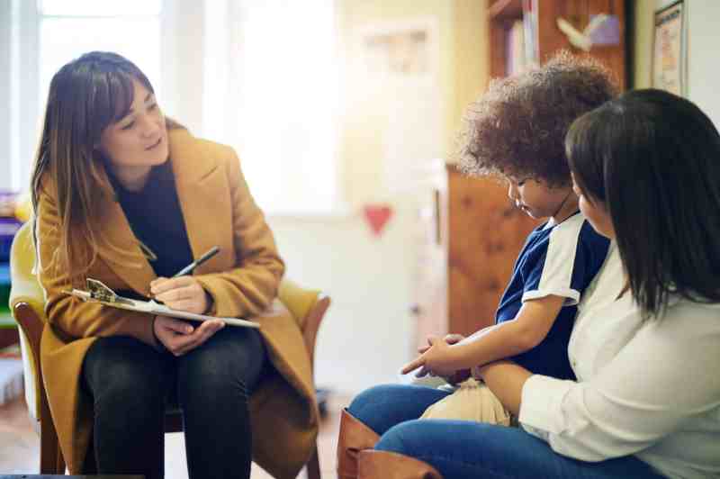 Therapist engaging with a child and parent in a cozy setting