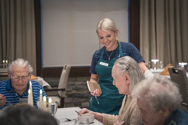 Staff serving dinner to residents in a dining area