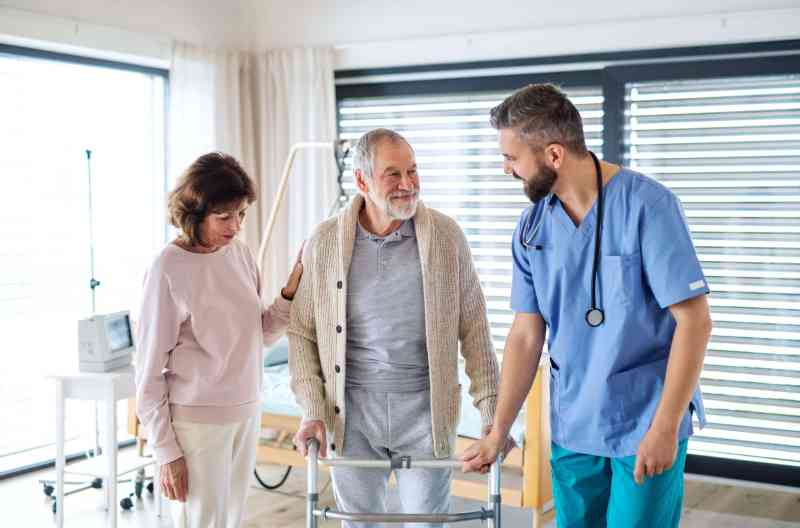 A caregiver assisting a resident with a walker in a bright room