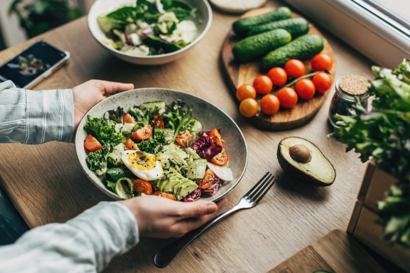 A person holding a fresh salad bowl with various ingredients