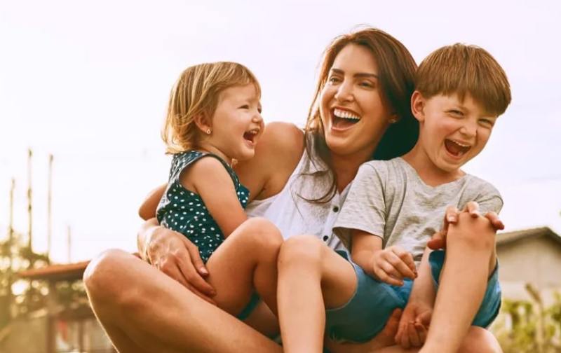 Mother and children laughing outdoors