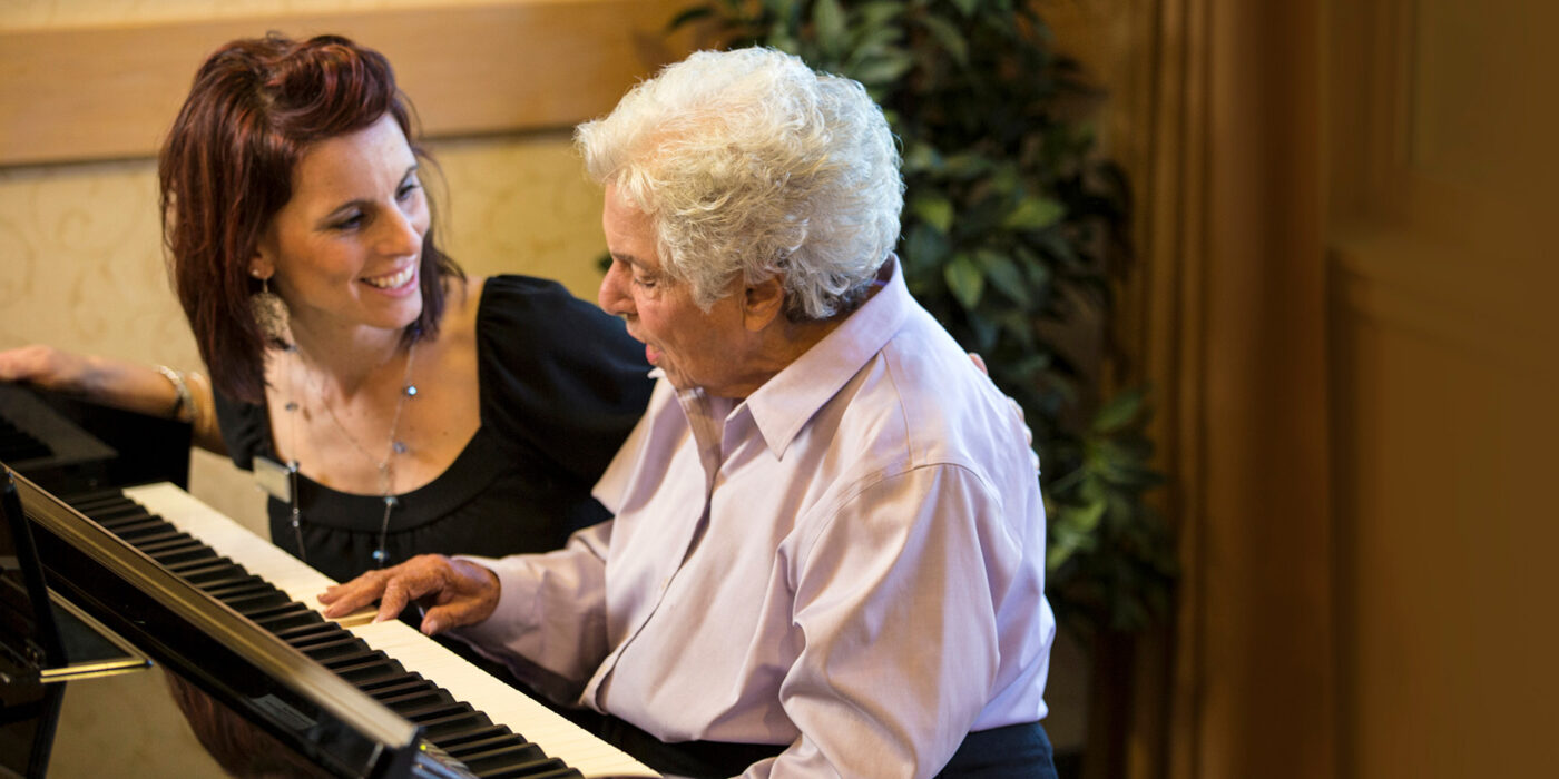 Resident and staff member playing piano together