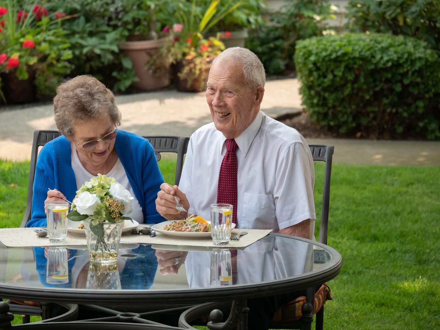 Residents enjoying a meal outdoors in a garden setting.