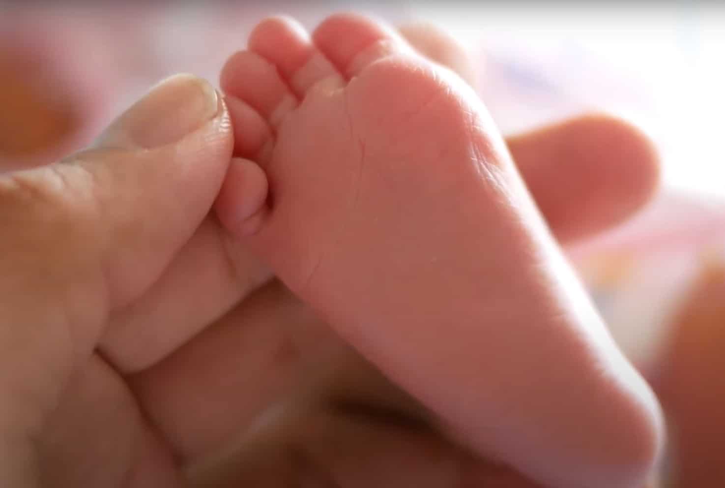 A close-up of a baby's foot being held