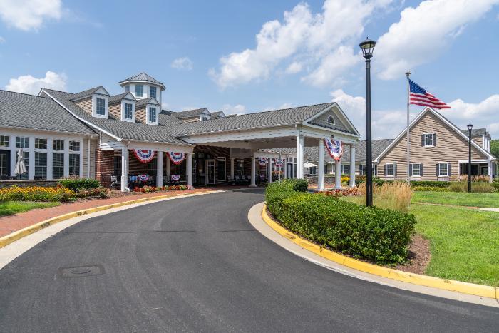 Entrance view of Alto Overland Park with flower beds and American flag