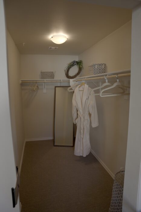 A private room closet with a robe and mirror