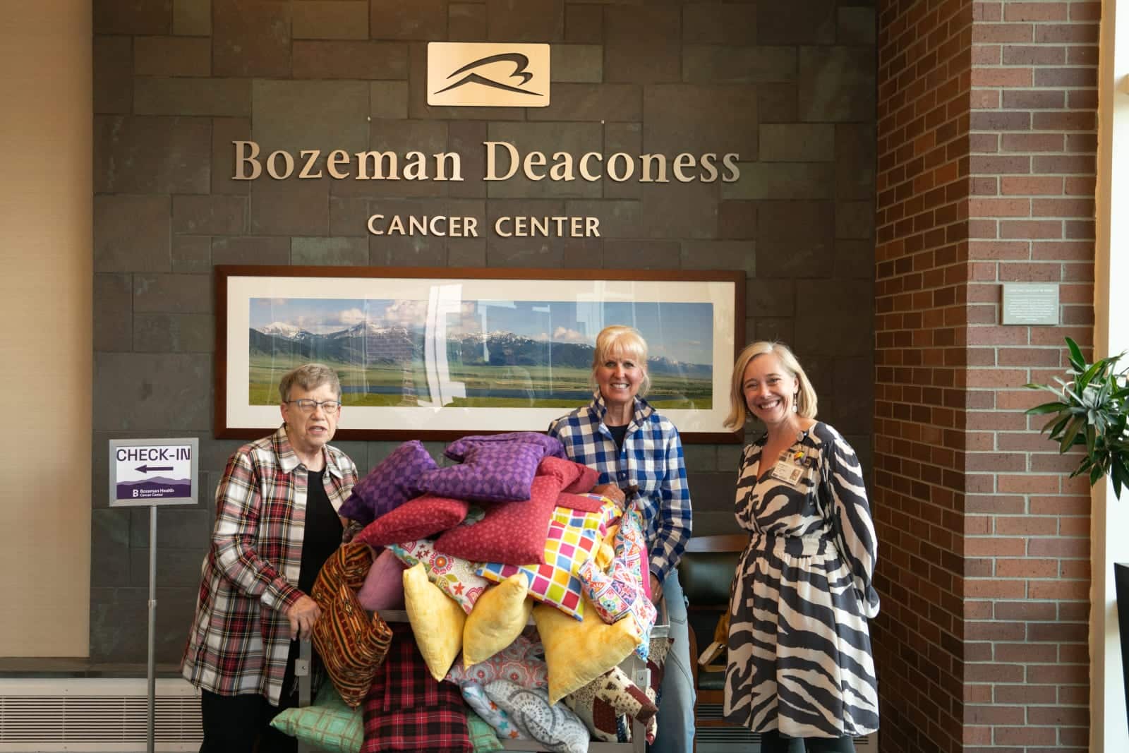 Three women holding a large pile of colorful blankets