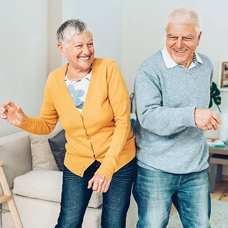 Two seniors dancing happily indoors