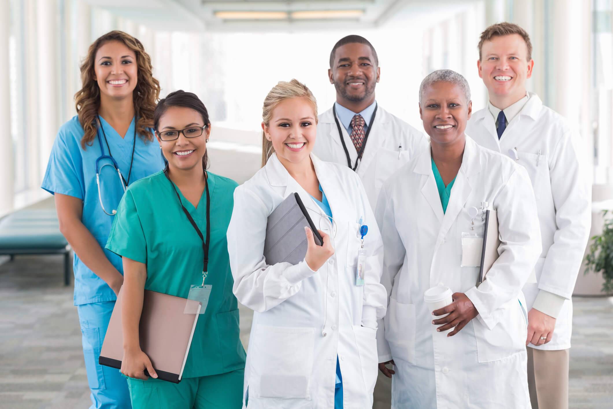 A diverse group of smiling healthcare professionals in a well-lit hallway