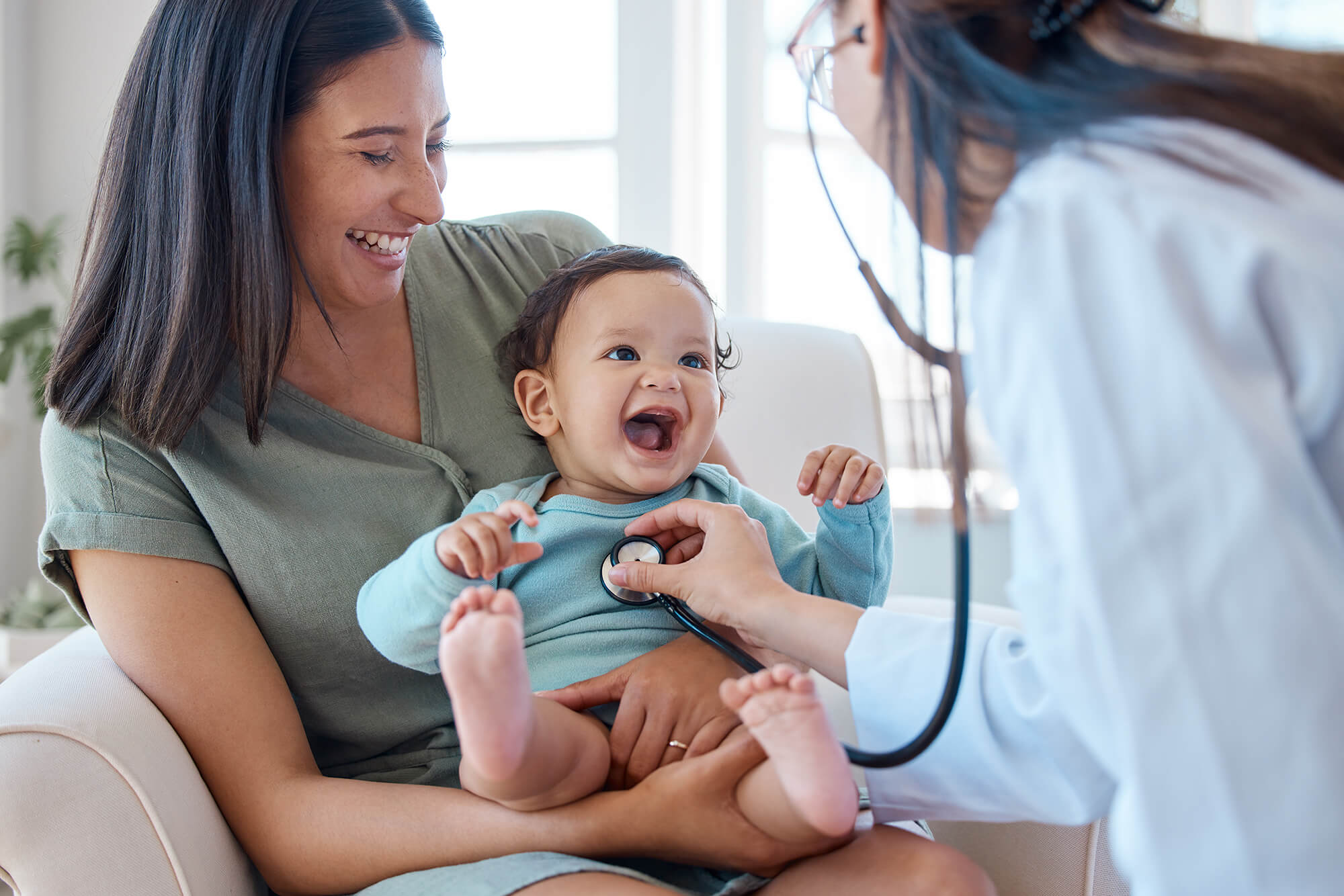 A mother holding her baby while a doctor checks the baby