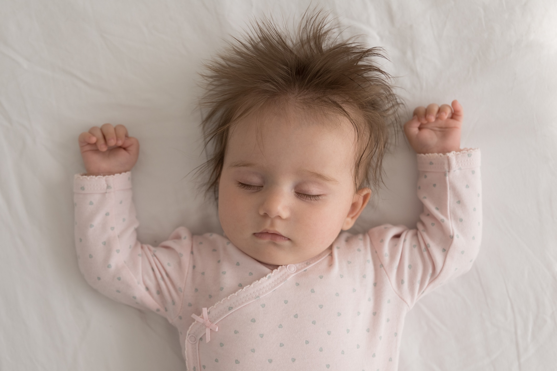 A baby sleeping on a white surface