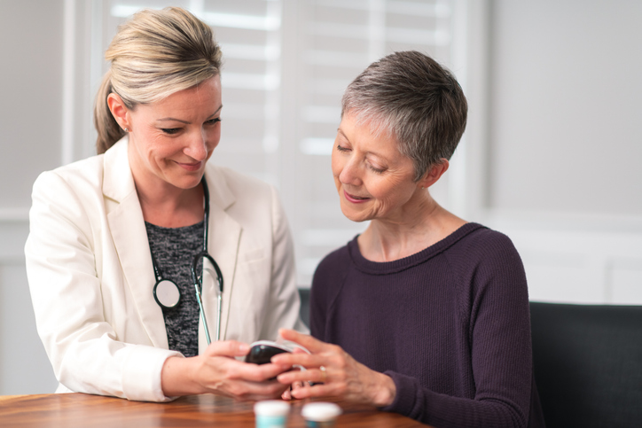 A caregiver assisting a senior resident in a bright room