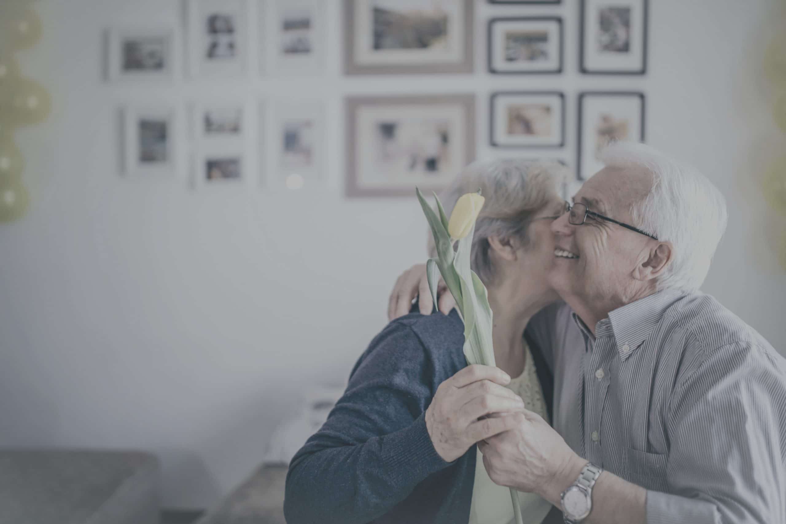 Senior couple celebrating with a flower in a decorated room