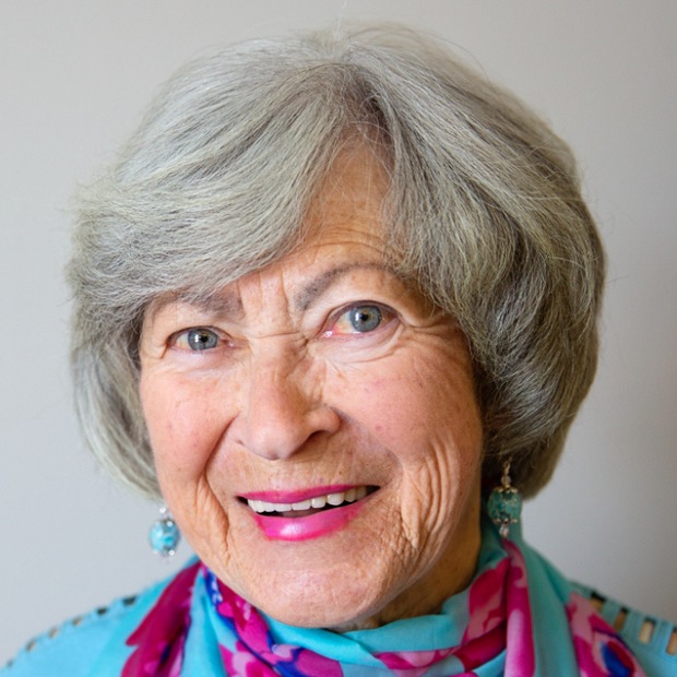 A smiling elderly woman with gray hair and colorful scarf