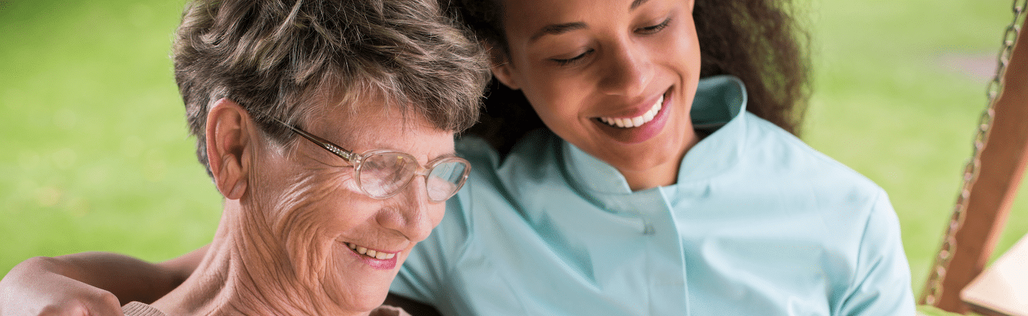 A resident and staff member sharing a joyful moment outdoors