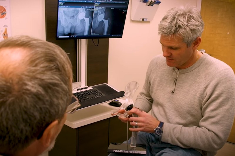 A doctor showing a model to a patient in a medical setting.