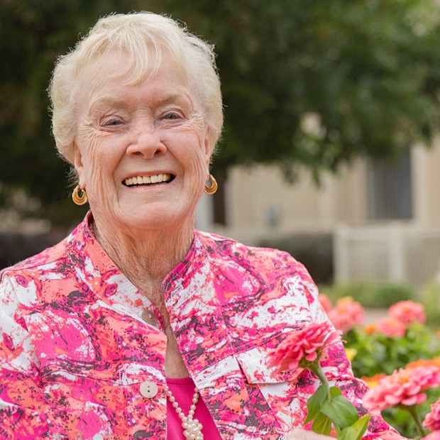 Smiling senior woman in a garden with flowers