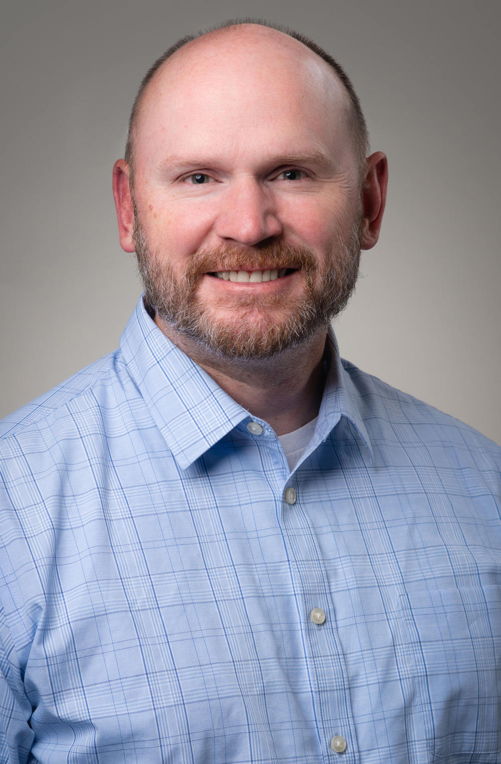 Male staff member smiling in a button-up shirt