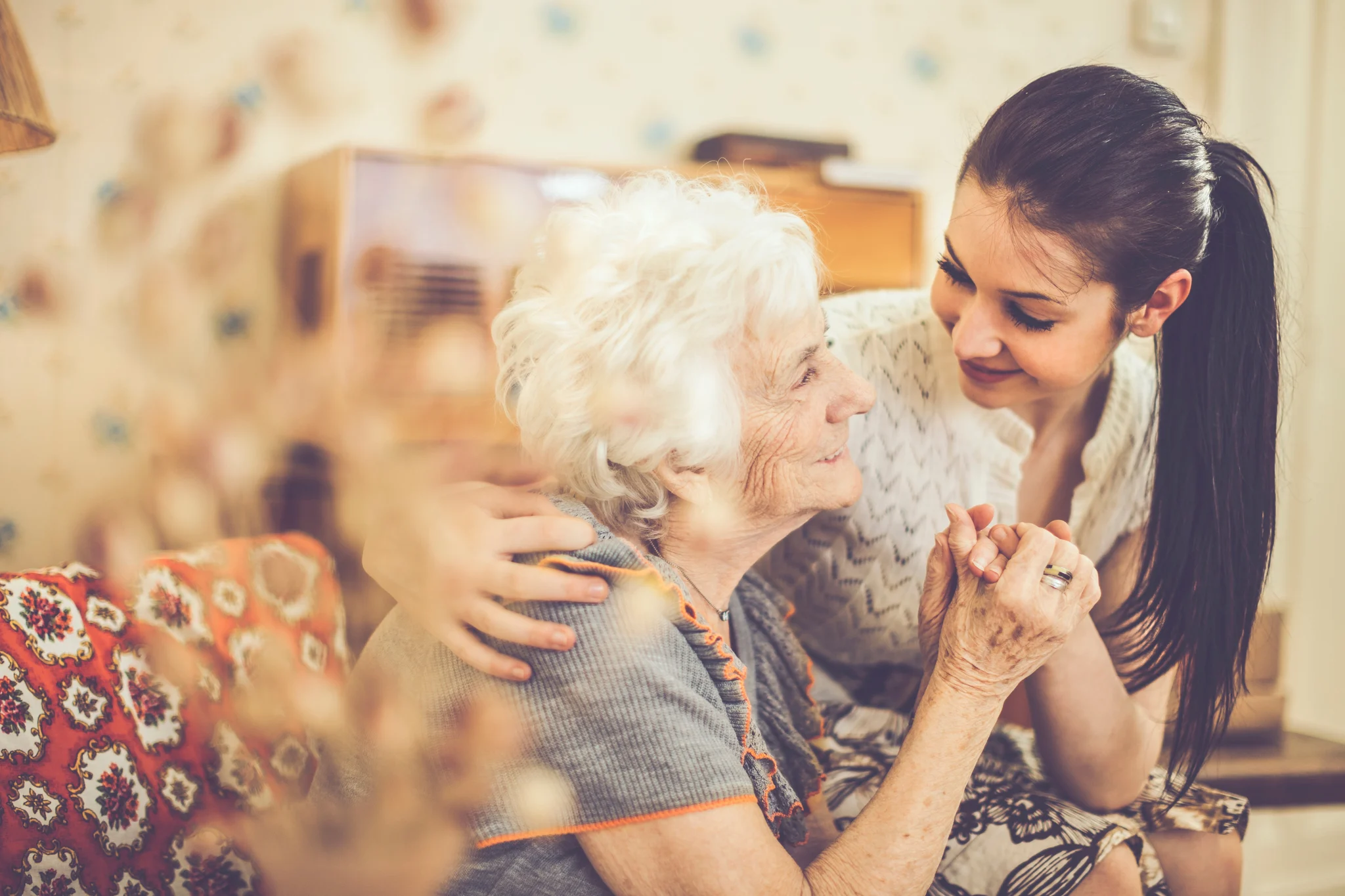 A caregiver smiling while holding hands with an elderly resident