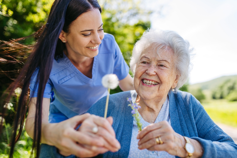 Caregiver and resident enjoying flowers outdoors