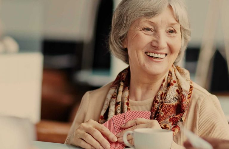 A smiling senior woman holding playing cards
