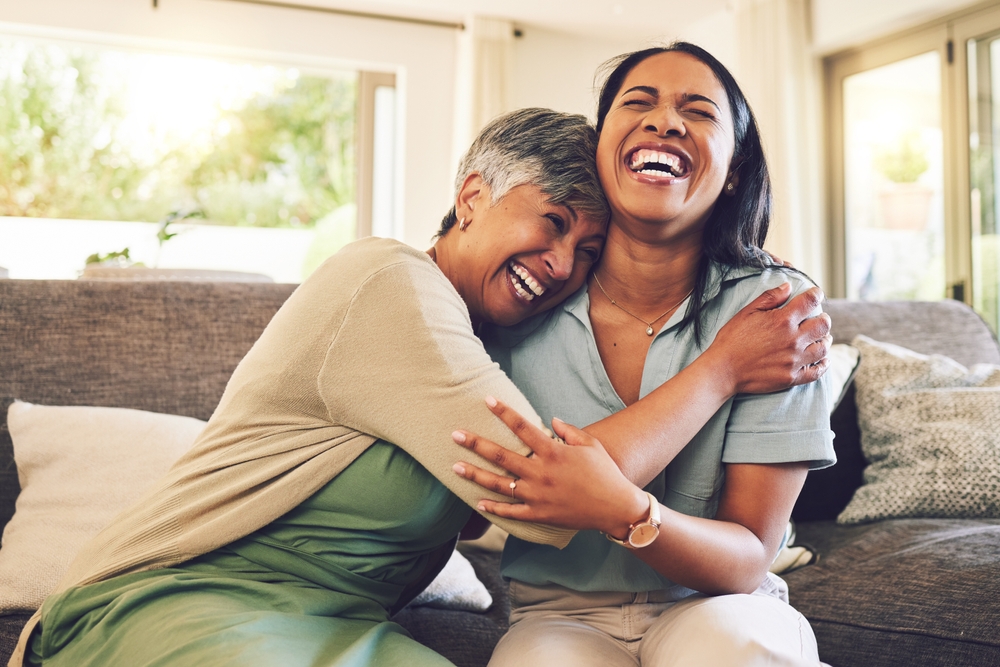 Two women joyfully embracing in a cozy living space