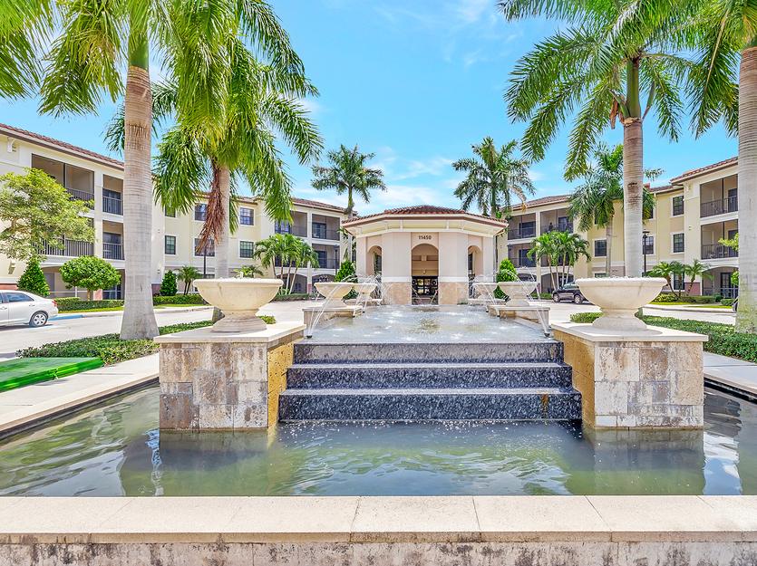 Exterior view of a senior living facility with fountains and palm trees