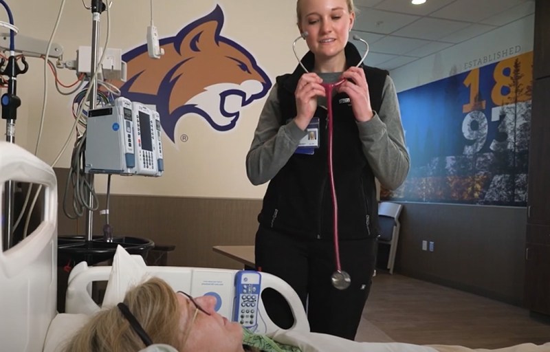 A staff member using a stethoscope with a resident in a room